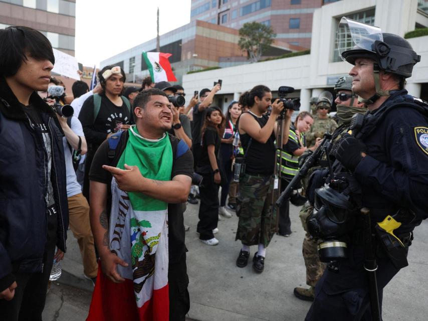 Un manifestante hace un gesto mientras agentes del orden hacen guardia cerca del edificio federal Edward R. Roybal en Los Ángeles, California.