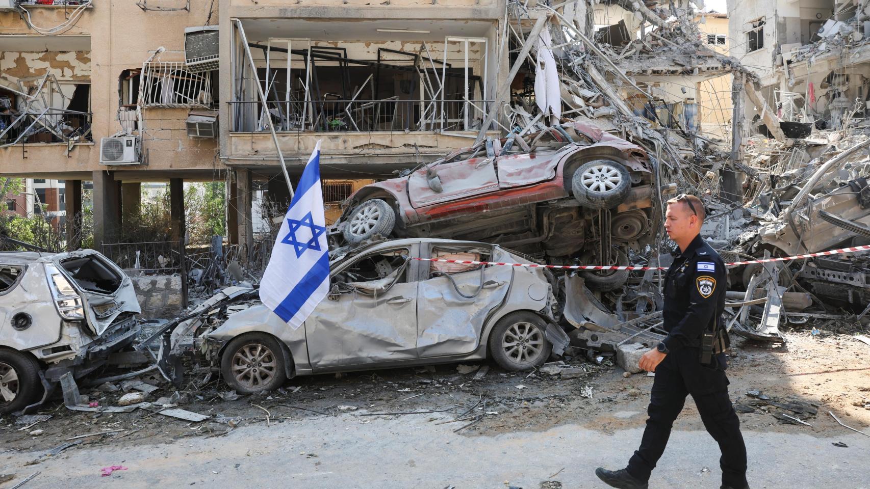 Un agente de policía israelí pasa junto a vehículos dañados en el lugar del impacto de un misil iraní contra Israel, en Ramat Gan, Israel.