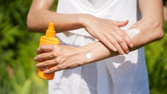 Una persona aplicándose protector solar.