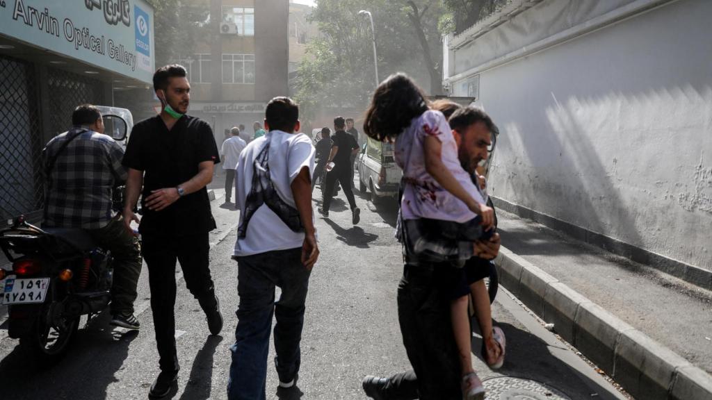 Un grupo de gente corre  por la calle tras un ataque de Israel, en Teherán.
