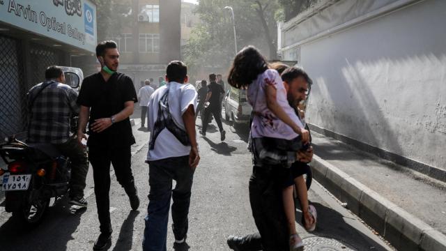 Un grupo de gente corre  por la calle tras un ataque de Israel, en Teherán.