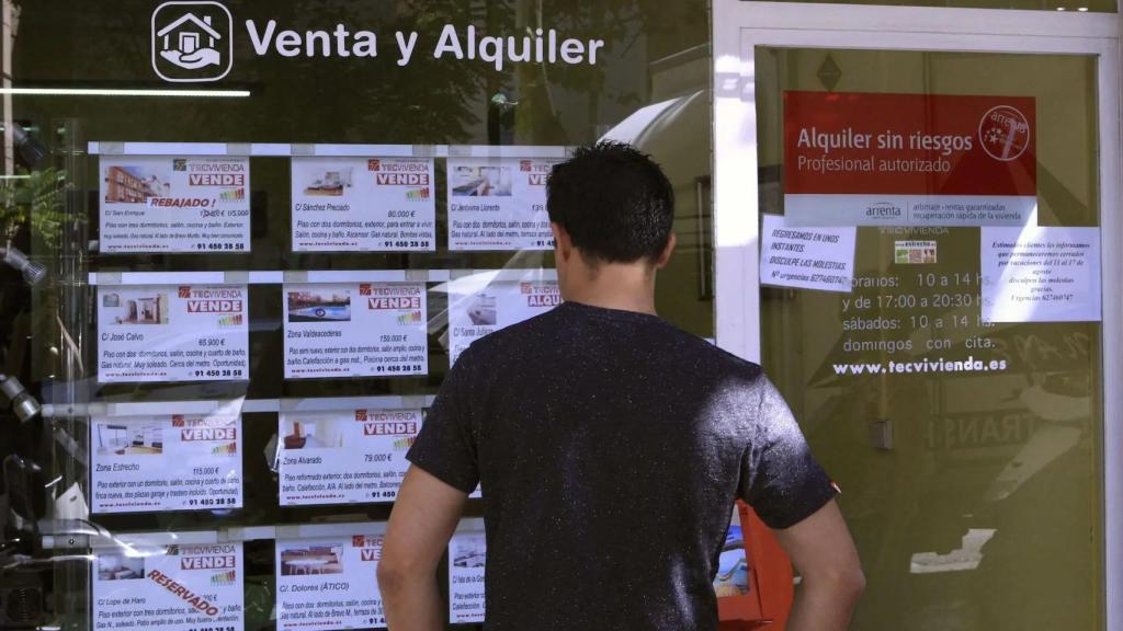 Un hombre observa precios de vivienda de compra y alquiler en una inmobiliaria