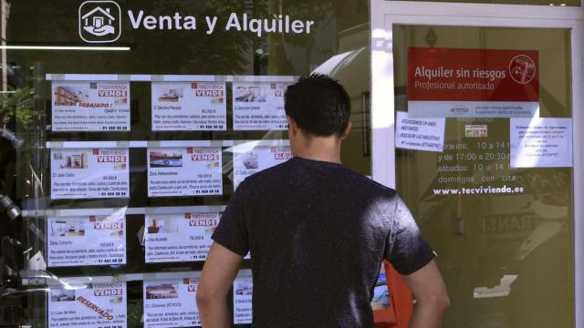 Un hombre observa precios de vivienda de compra y alquiler en una inmobiliaria