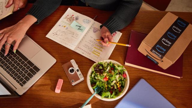 Una joven estudiando junto a un paquete con el logo de Amazon Prime.