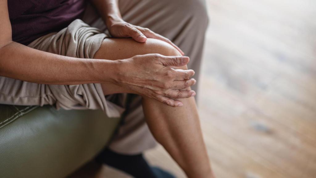 Mujer tocándose la rodilla.