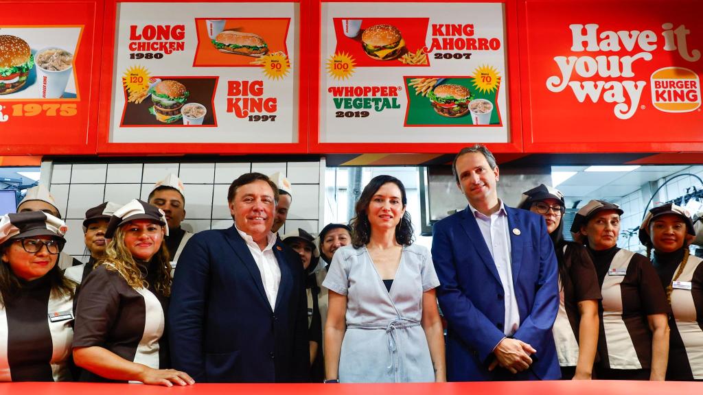 Empleados del Burger King de la Plaza de los Cubos con el uniforme de 1975, la presidenta de la Comunidad, Isabel Díaz Ayuso, y altos cargos de Restaurant Brands Europe, Gregorio Jiménez (izq.) y Borja Hernández de Alba, este martes.
