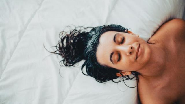 Mujer con el pelo mojado sobre la cama.