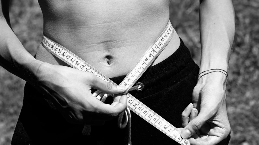 Imagen de archivo de una mujer midiéndose la cintura.