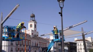 Dos operarios durante la instalación de los nuevos toldos de la Puerta del Sol.