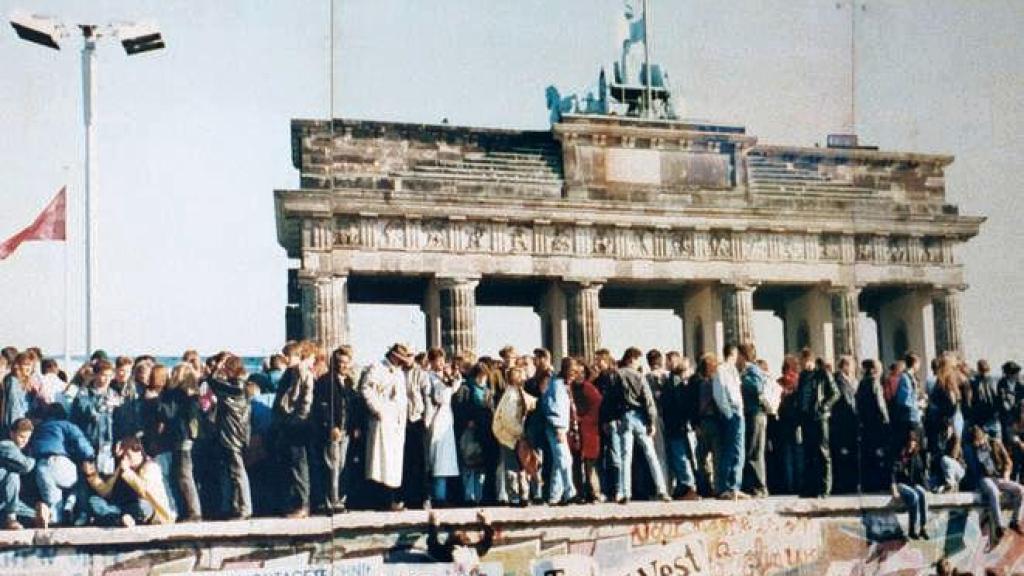 El 9 de noviembre de 1989 cae el Muro de Berlín y ciudadanos de Alemania Oriental (sobre el muro) saludan a sus vecinos de Alemania Occidental.