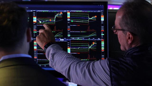 Dos operadores de la Bolsa de Nueva York miran unos gráficos en una pantalla.