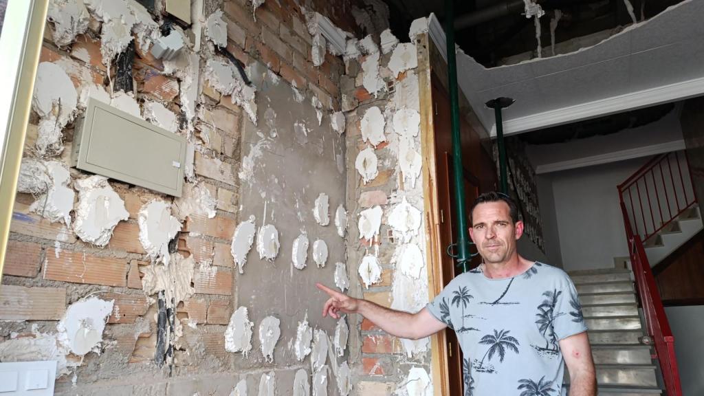 José, vecino del bloque, muestra cómo ha quedado la entrada a sus viviendas tras la deflagración.