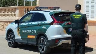 Un agente de la Guardia Civil, junto a su vehículo.