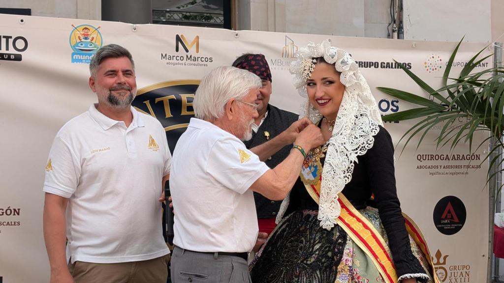 Juan Rubio coloca la insignia del centenario a la Bellea del Foc Adriana Vico.