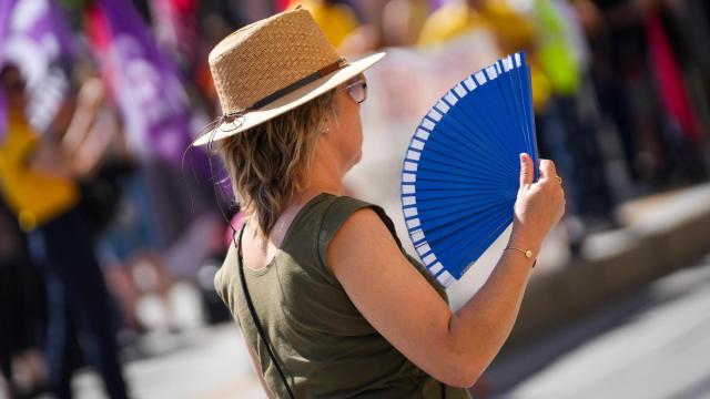 Una mujer se abanica por las calles de Sevilla.