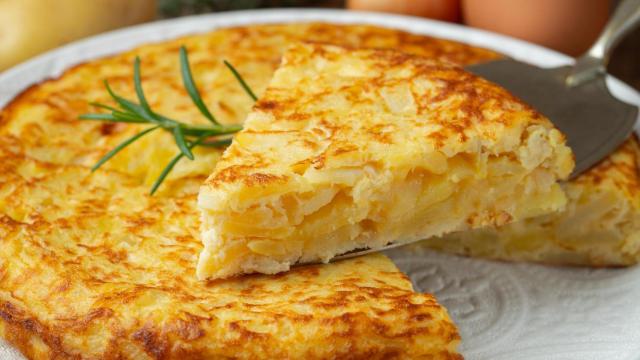 Una persona cuajando una tortilla de patata (Imagen de archivo)