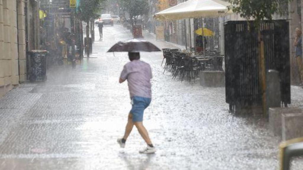 Un hombre se protege de una tormenta de verano en Madrid.
