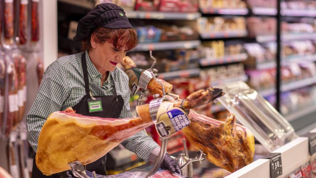 Una trabajadora de Mercadona cortando jamón.