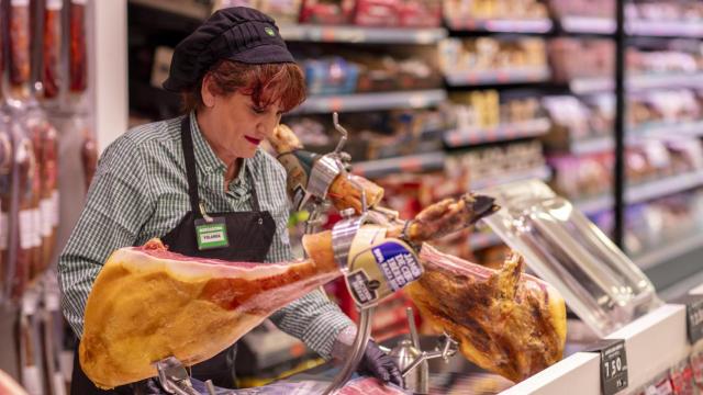 Una trabajadora de Mercadona cortando jamón.