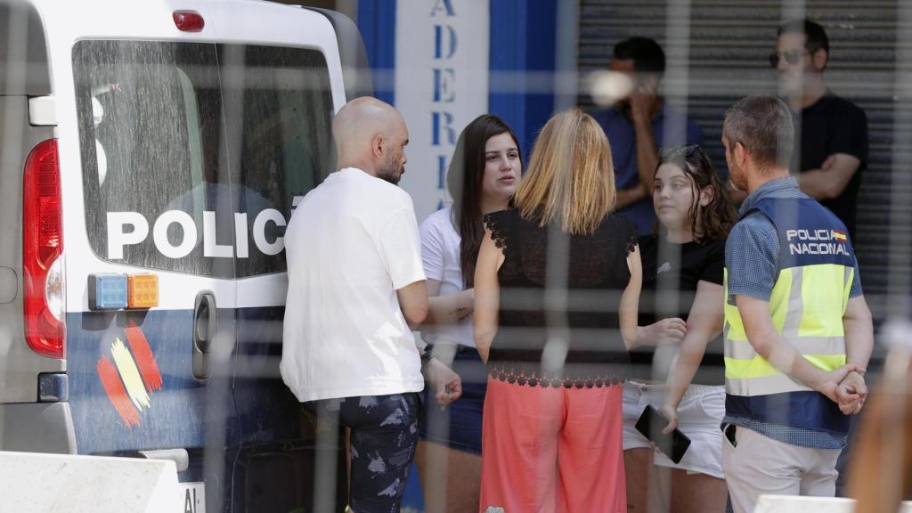 El hermano y la cuñada de la víctima junto a efectivos de Policía Nacional a las puertas del inmueble. EFE/Manuel Bruque
