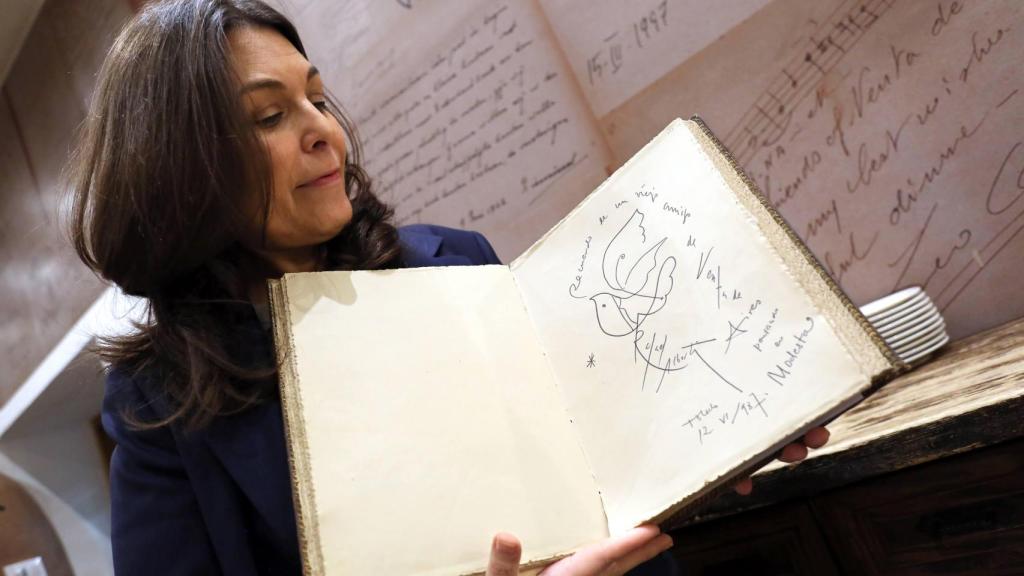 Cuca Díaz de la Cuerda mostrando la dedicatoria de Alberti en el libro de firmas del restaurante.