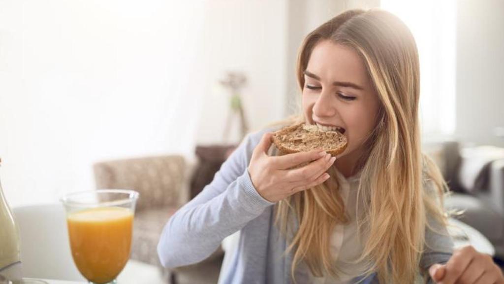 Mujer comiendo una rebanada de pan.