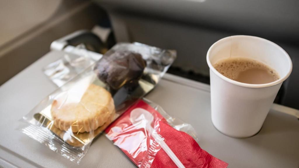 Unas galletas y un café en la mesilla desplegada de un avión