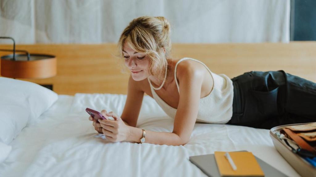 Imagen de archivo de una mujer con el móvil en la cama.