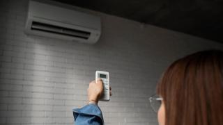 Una mujer usando el mando a distancia de un aire acondicionado