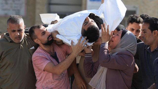 Gazatíes cargan el cuerpo de un palestino muerto en un ataque israelí.