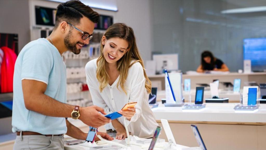 Unos clientes en una tienda de tecnología mirando los productos.