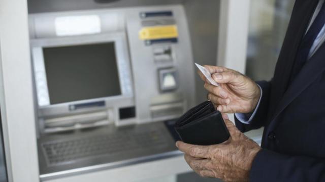 Imagen de archivo de un jubilado sacando dinero.