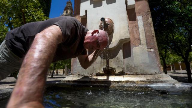 Un hombre se refresca en una fuente durante una ola de calor.