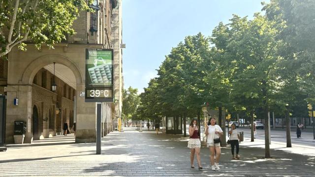 Dos jóvenes intentan luchar contra el calor de Zaragoza con ventiladores y abanicos.