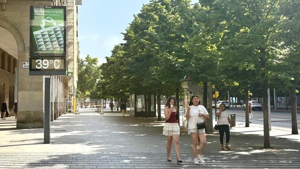 Dos jóvenes intentan luchar contra el calor de Zaragoza con ventiladores y abanicos.