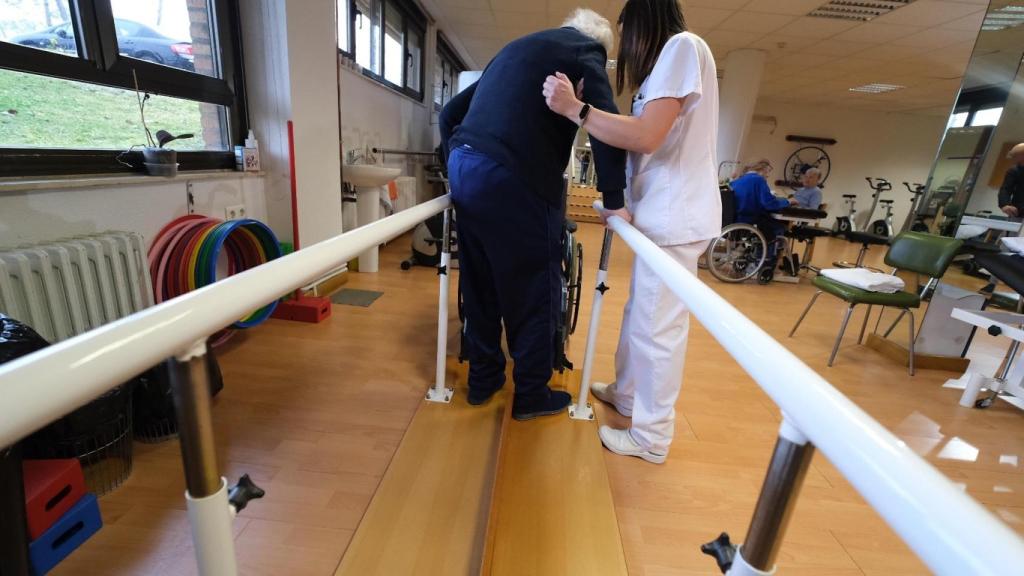 Una sanitaria ayuda a un anciano.