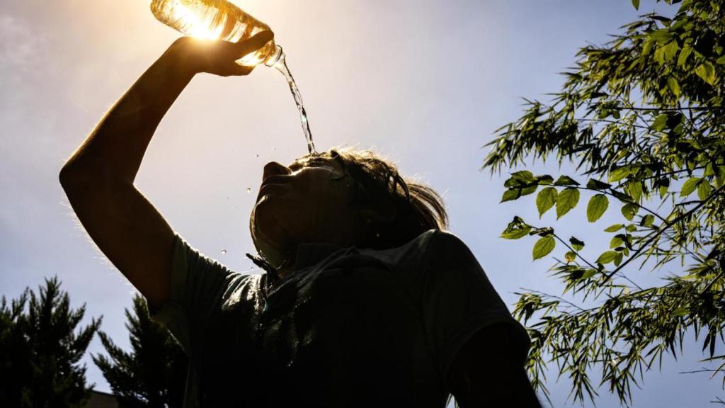 Un niño alivia el calor con una botella de agua.