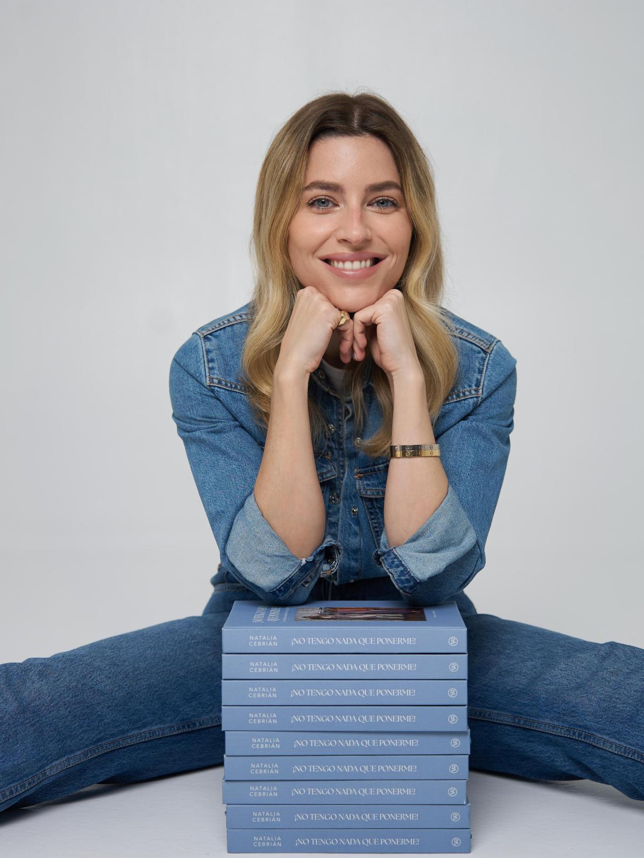 Nat Cebrián posa divertida junto a una pila de libros.