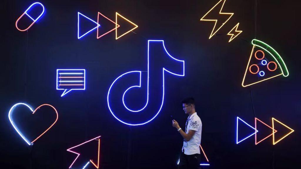 Un joven pasa junto a un cartel de TikTok (Douyin) durante una exposición en Hangzhou, China, en octubre de 2019.