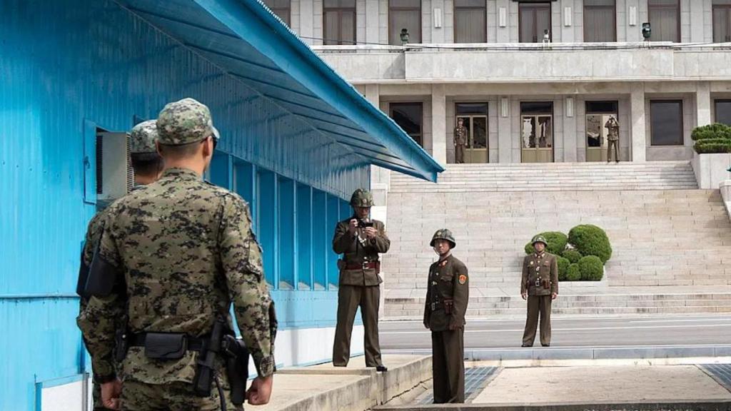 Soldados norcoreanos permanecen en el lado norcoreano, uno de ellos utilizando una cámara, mientras soldados surcoreanos los enfrentan en la frontera de la zona desmilitarizada (DMZ), en Panmunjom.