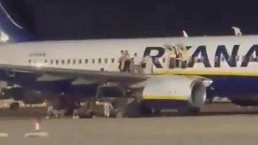 Los pasajeros del vuelo afectados abandonan el avión por las salidas de emergencias.