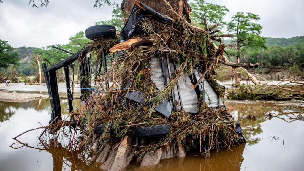 Un remolque empotrado en un árbol, consecuencia de las inundaciones en Texas.