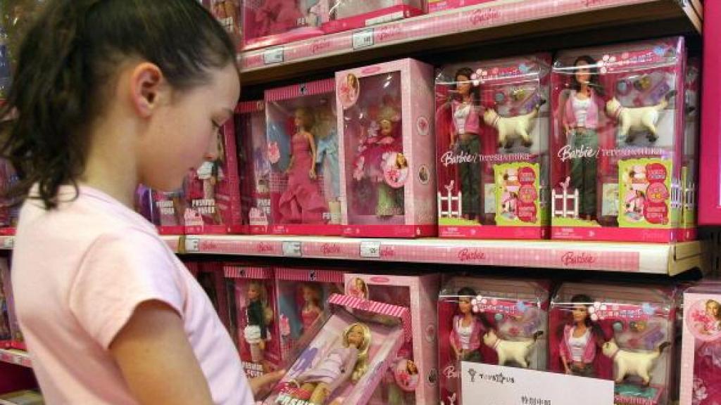 Imagen de archivo de una niña mirando Barbies en una tienda.