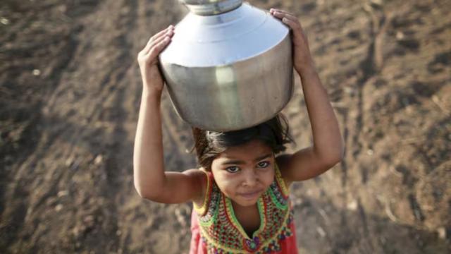 Una niña lleva una jarra de metal llena de agua por un campo en Latur, India. Existe un déficit de inversión anual de 4 billones de dólares para alcanzar los Objetivos de Desarrollo Sostenible de la ONU para 2030.