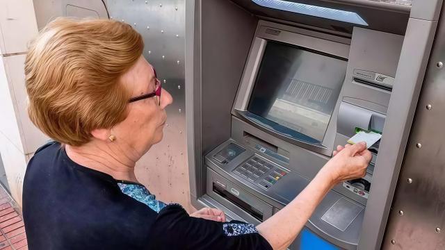 Una mujer sacando dinero de un cajero automático.