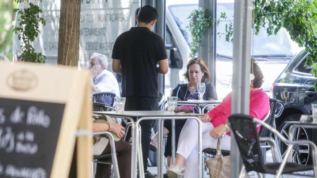 Un camarero atiende a varios clientes en la terraza de un restaurante en Madrid.