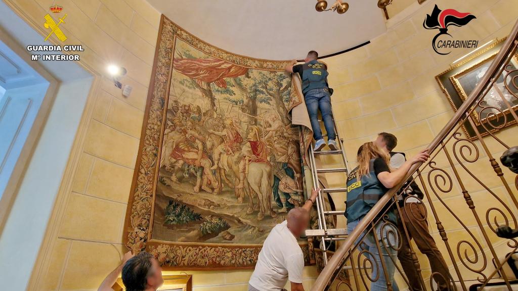 Varios agentes de la UCO de la Guardia Civil retiran un tapiz de una de las paredes de la mansión de los Kiss en Italia.