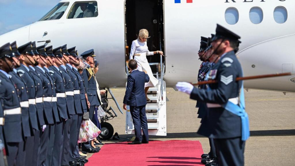 Emmanuel Macron intentando ayudar a su mujer a bajar del avión tras aterrizar en Londres.