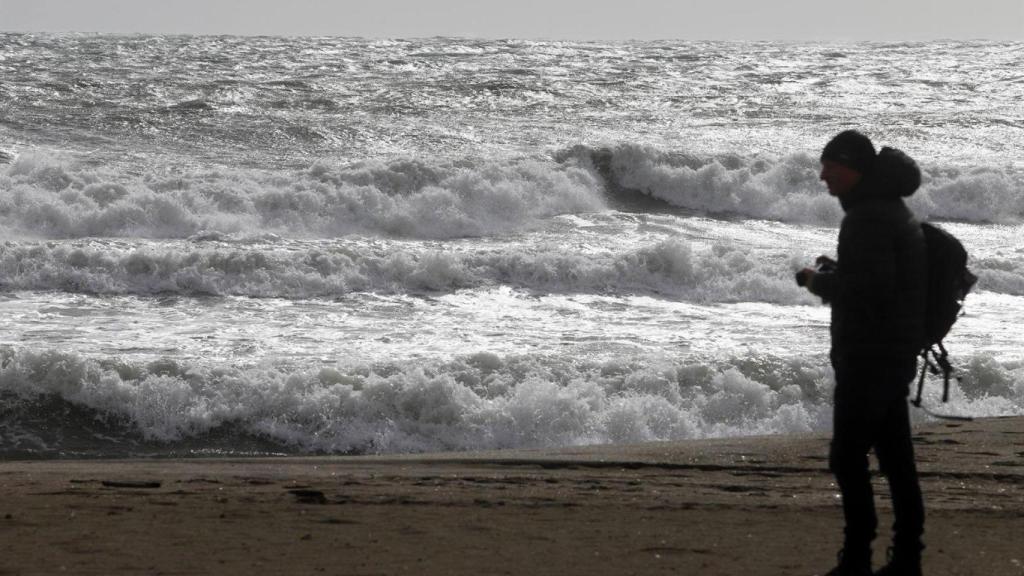 Una persona en la playa de la Malagueta visualizando el temporal en una imagen de archivo.
