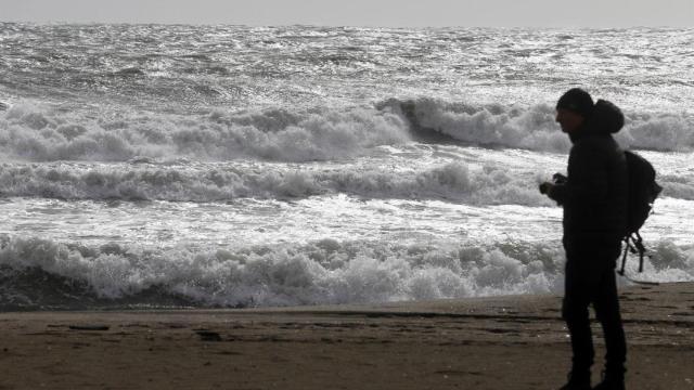 Una persona en la playa de la Malagueta visualizando el temporal en una imagen de archivo.
